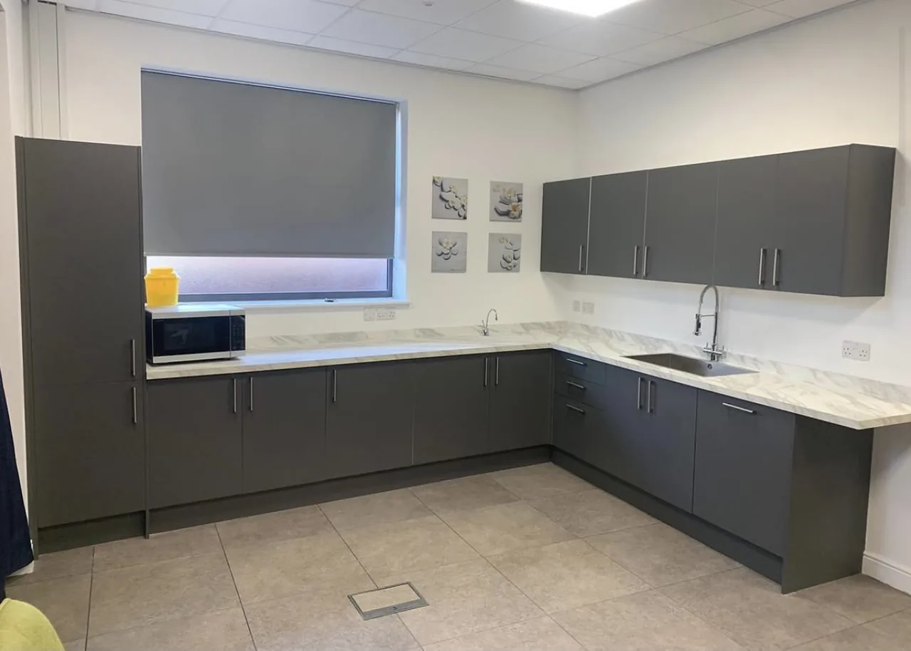 Anthracite handleless kitchen with a marble-effect worktop fitted in a staff kitchen