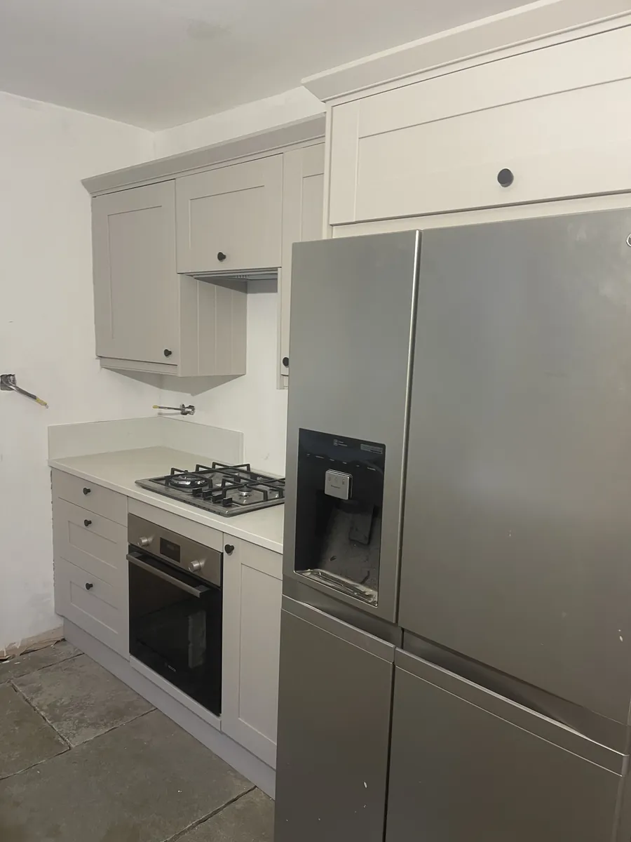 Shaker kitchen units and a bridging unit fitted around an American fridge-freezer in a period property