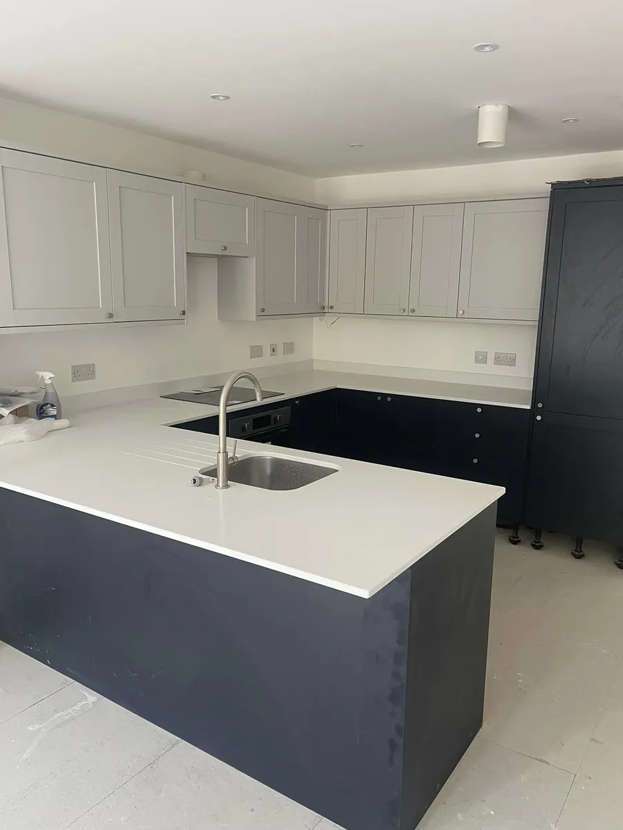 U-shaped navy and grey kitchen with a white quartz worktop and peninsula