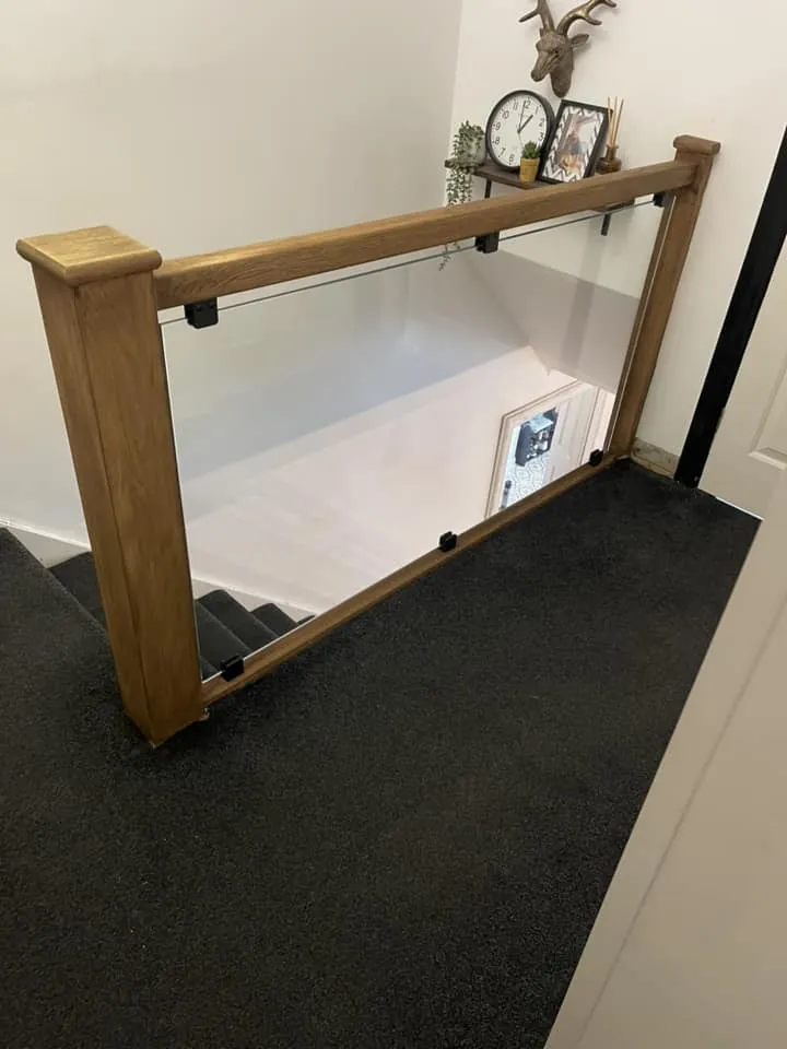Oak newel posts and handrail with toughened glass infill panels fitted on a landing