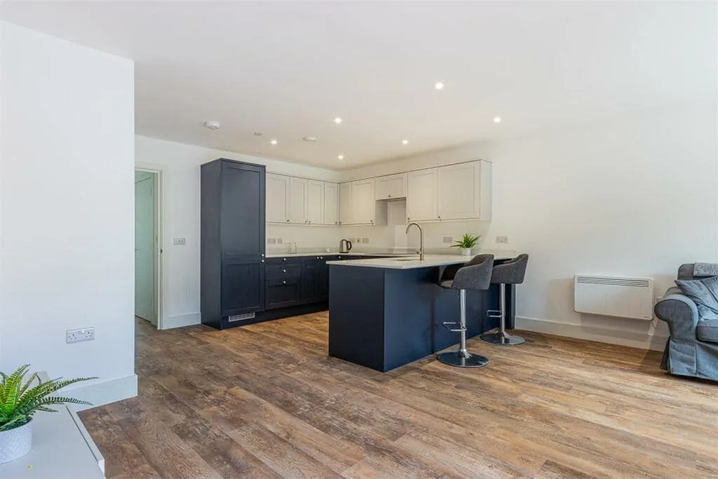 Open-plan kitchen with a navy breakfast bar peninsula and cream wall units
